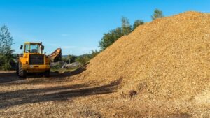 wood chipper driving next to a massive pile of wood chips