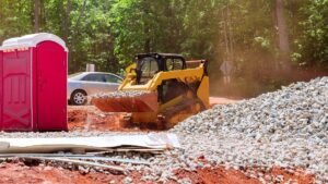 Compact track loader transporting gravel at an active construction site.